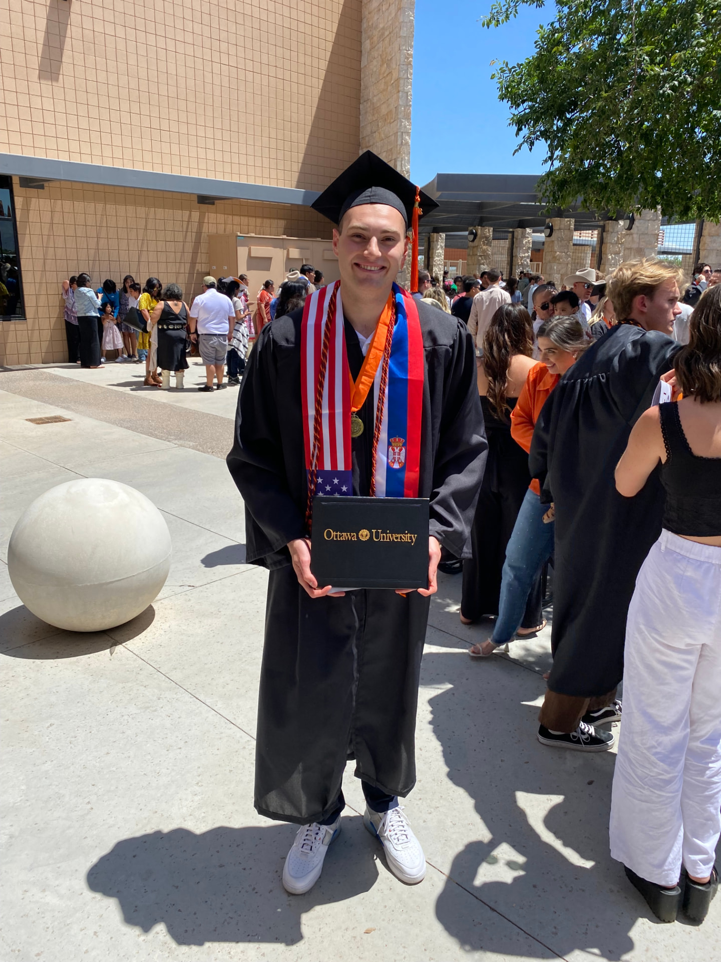 Pavle Ristić in graduation cap and gown holding an Ottawa University diploma cover